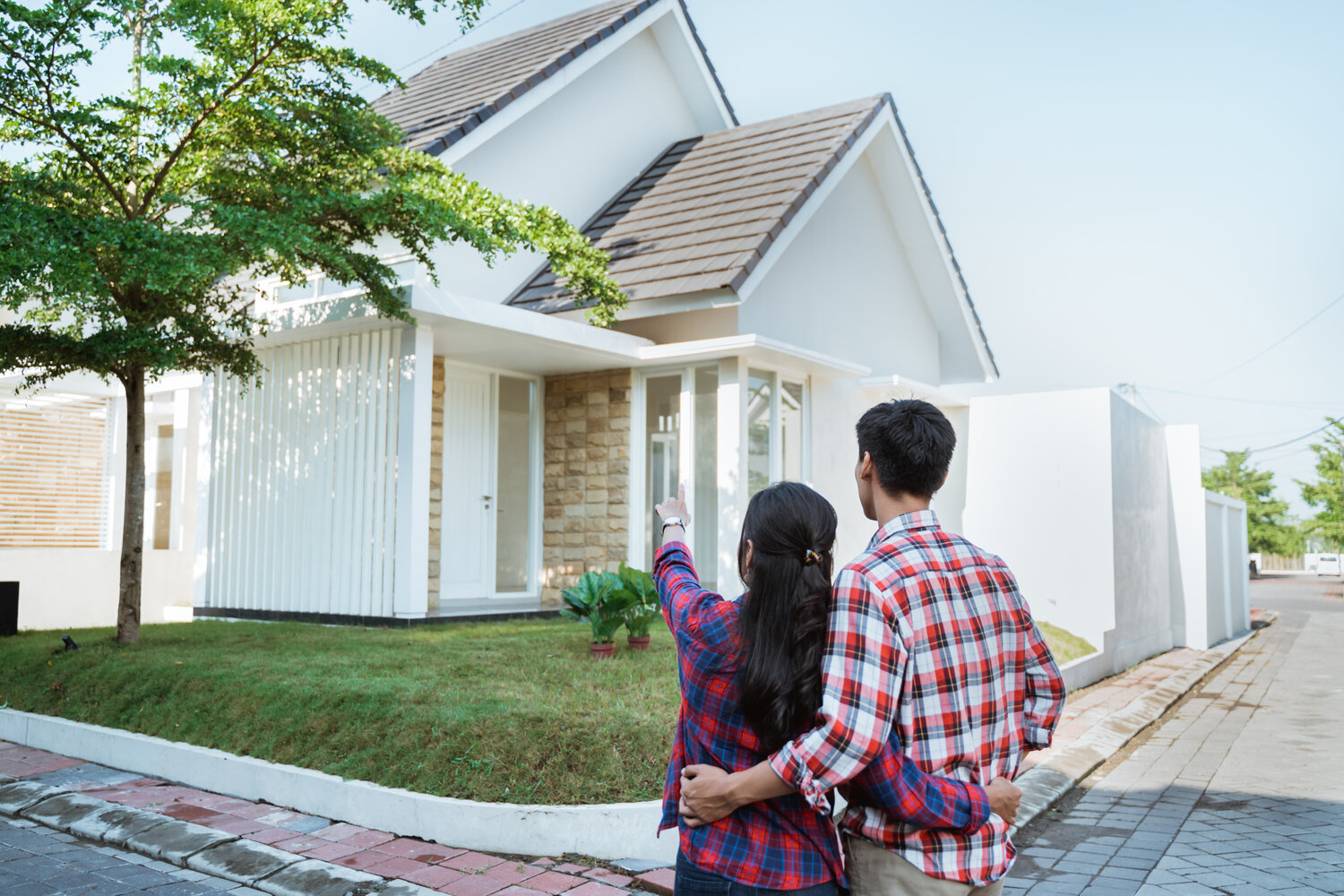 A couple embracing each other and looking at their new home.