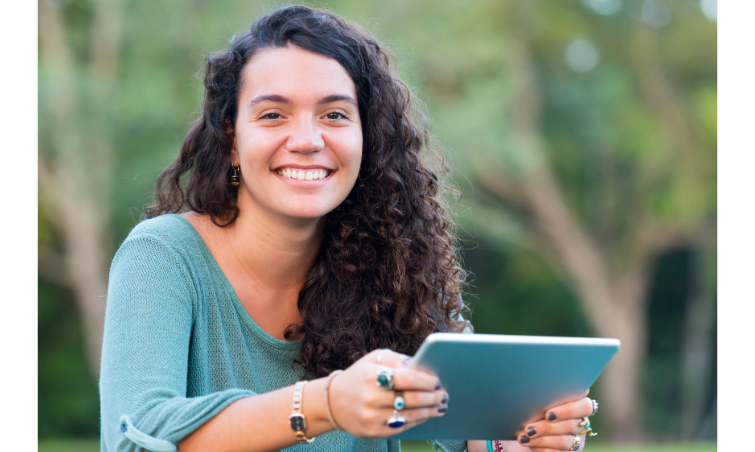 female college student sitting outdoors with tablet in green top