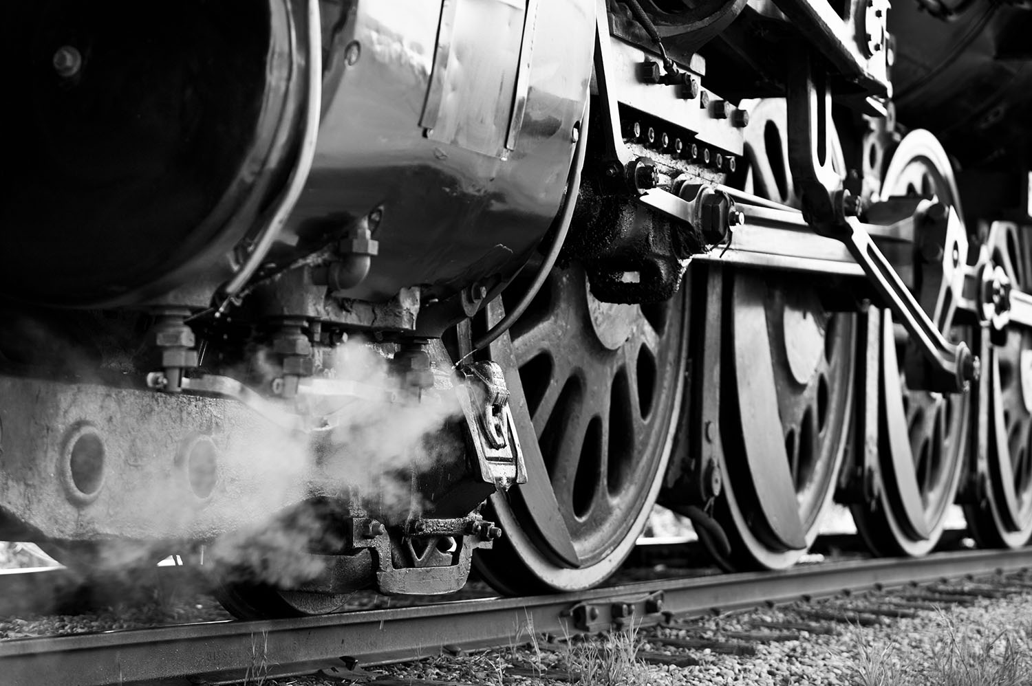 A black and white photo of a train locomotive's wheels.