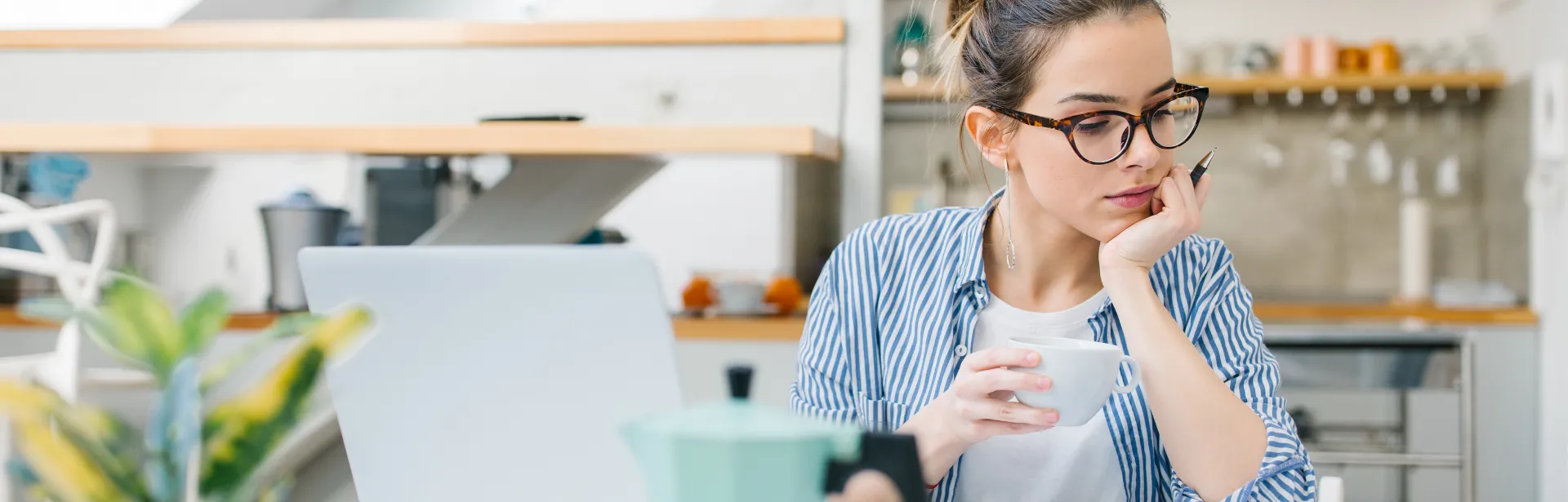 A women holding a coffee cup with her face resting on her hand.