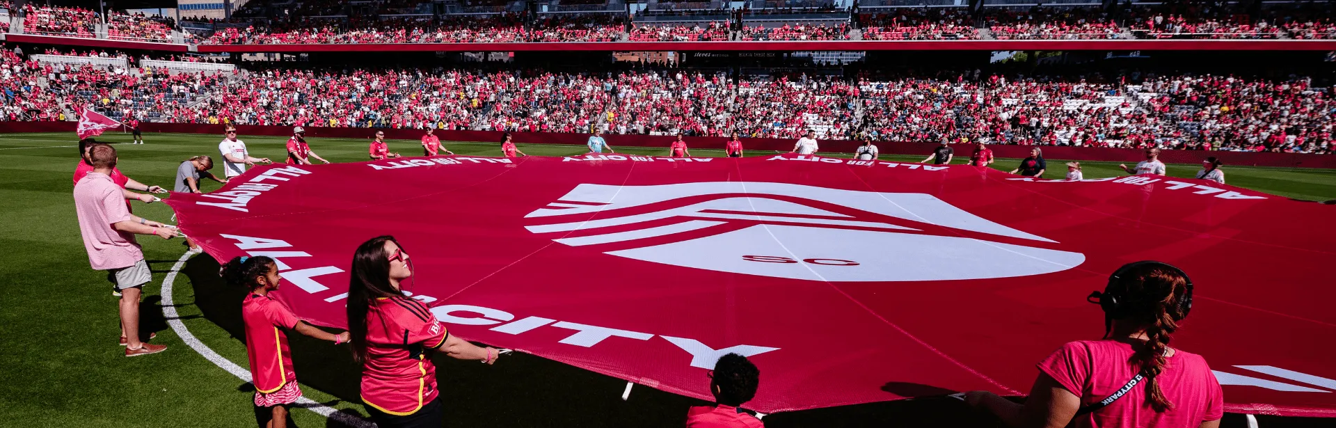 Several people hold a large piece of fabric at a sports event.