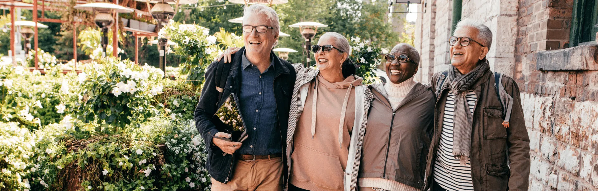 Four senior people stand together in a garden.