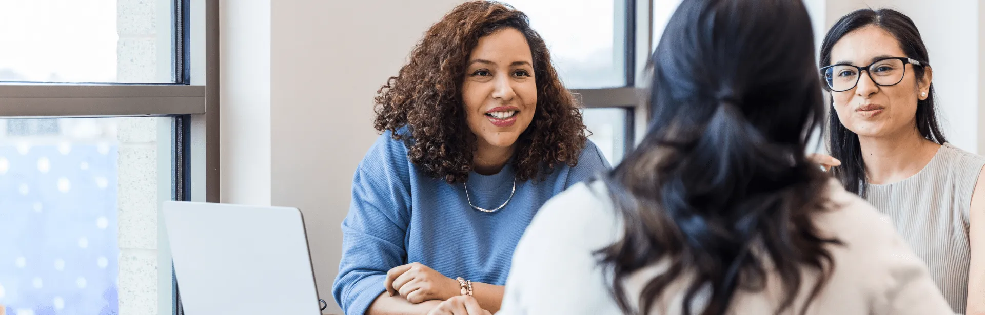 Three woman at a meeting in an office setting.