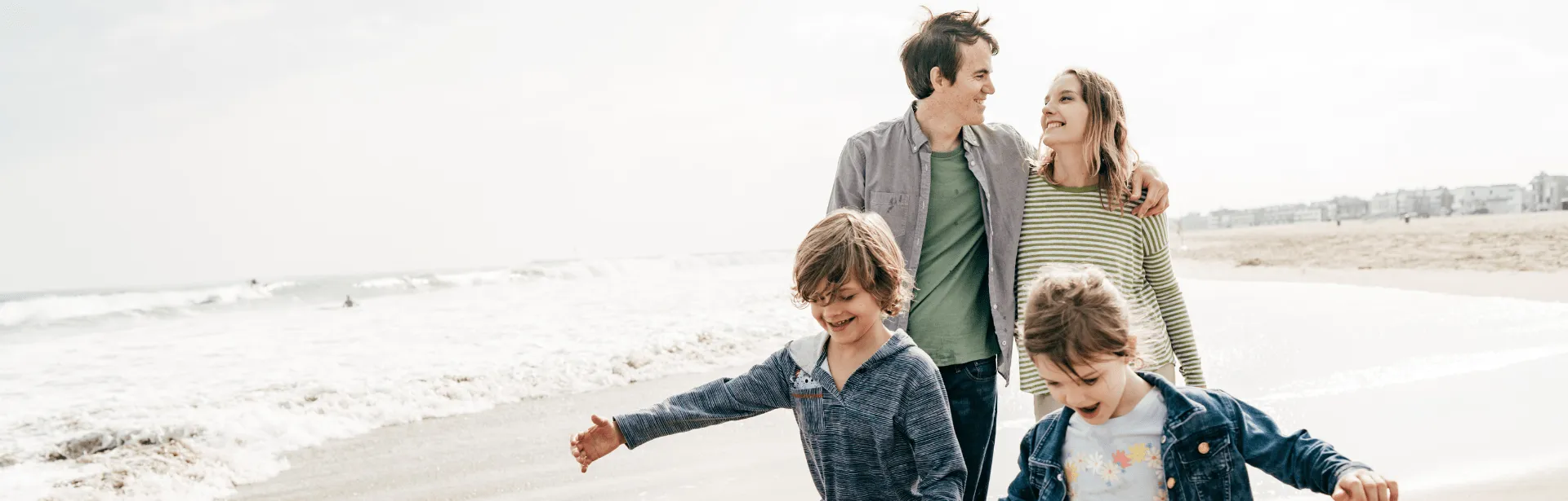 Two parents and their two children walking down the beach.