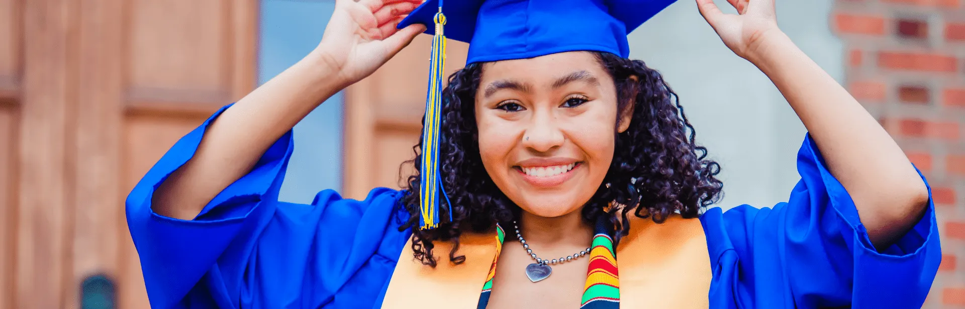 A woman wearing a graduation gown and smiling.