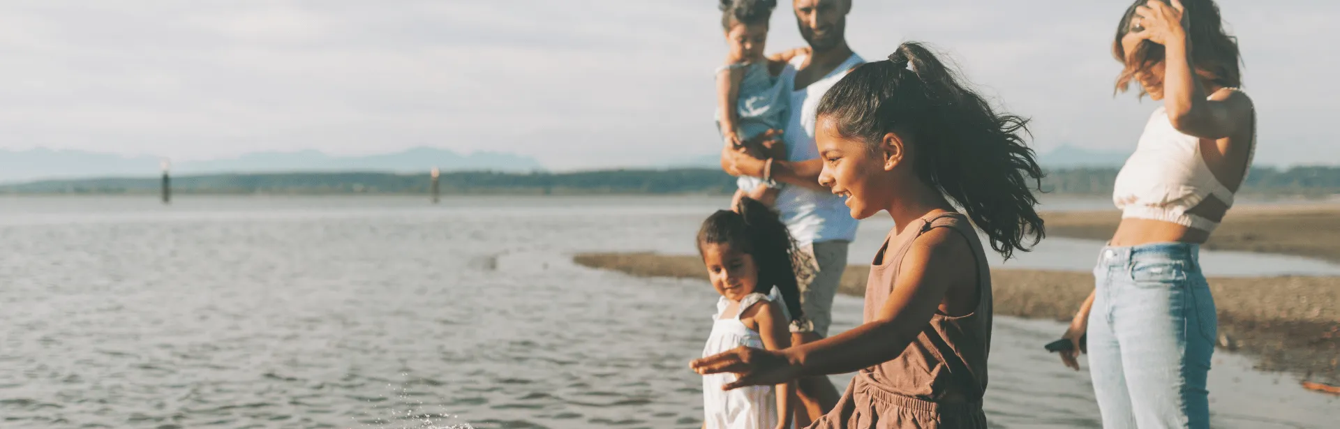 A family on a beach, playing in the ocean water.